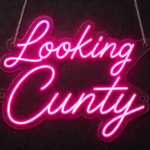 Looking Cunty neon sign in hot pink LED neon script on clear acrylic, hanging on chains against a dark wall