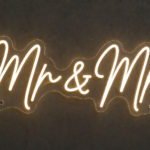 Mr and Mrs neon sign in warm white LED neon script on contour-cut clear acrylic with standoff fixings, mounted on a dark wall